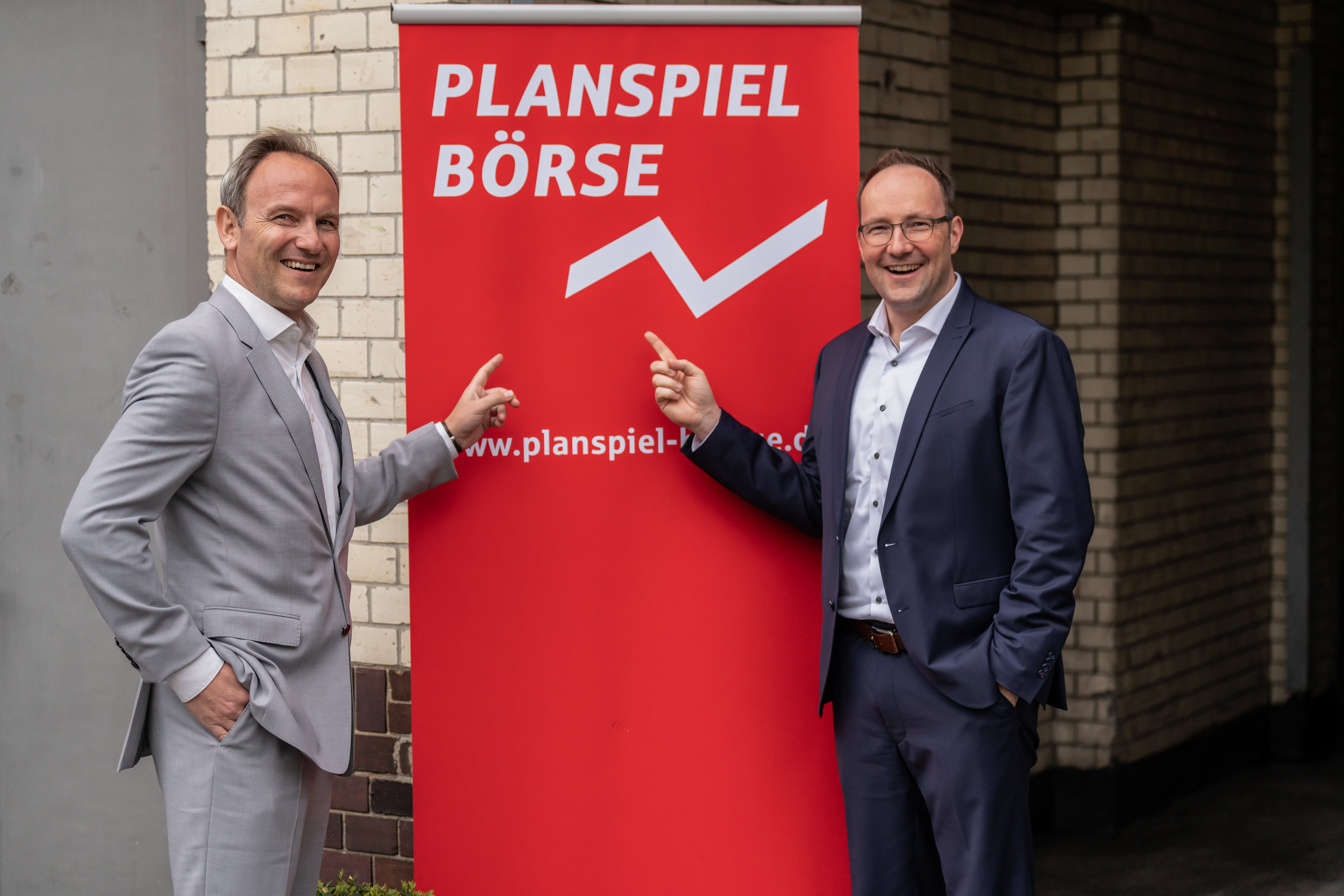 Zwei Männer stehen neben Banner mit der Aufschrift 