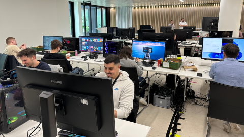 Blick auf junge Menschen, die in großem Raum vor Computern sitzen und zocken