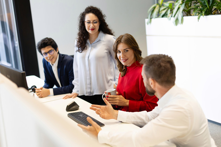 Deka employees sitting in front of a PC and having a conversation