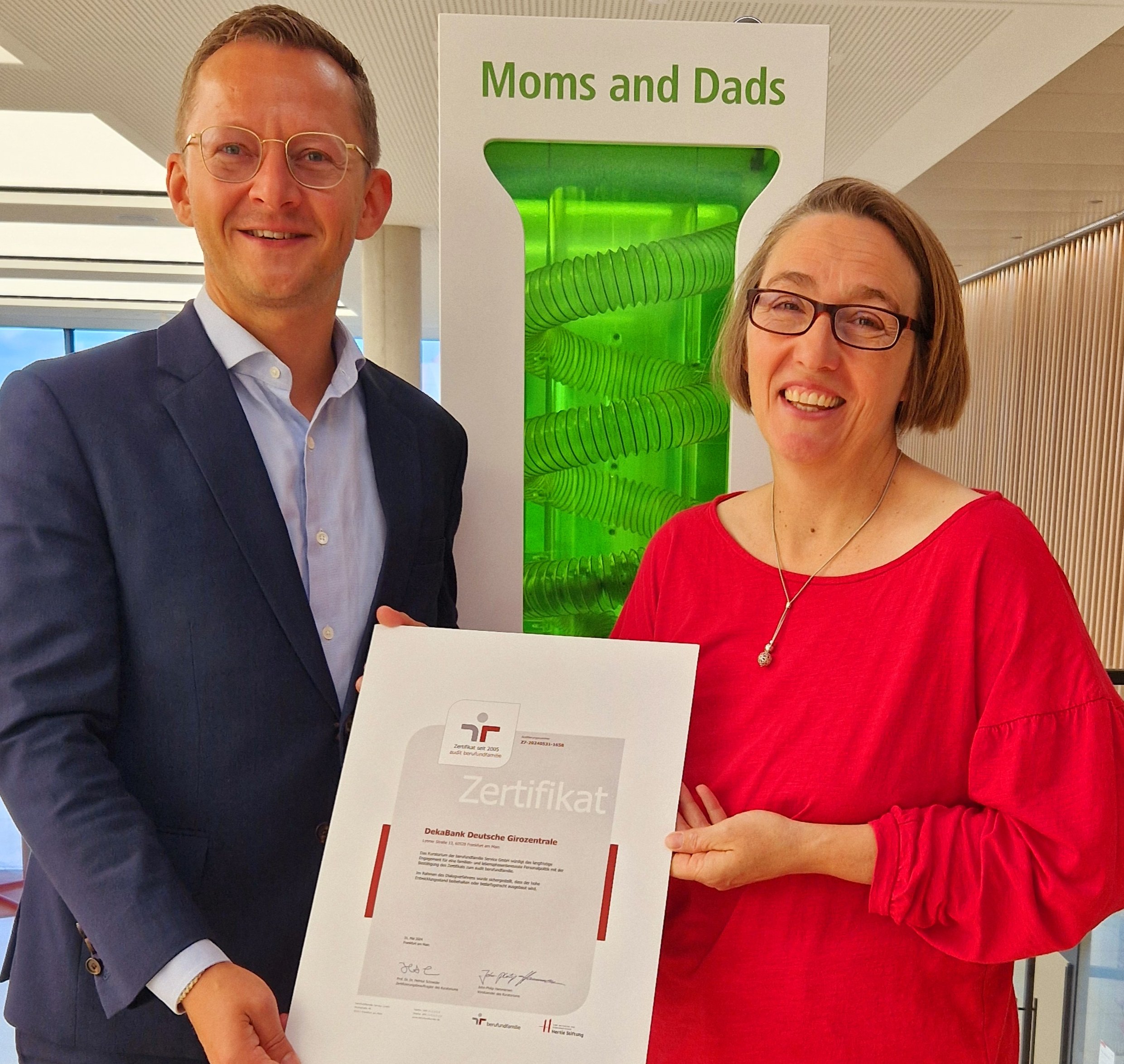 Steffen Hahn und Melanie Zeller-Rudolf, beide Deka, halten das Zertifikat von berufundfamilie