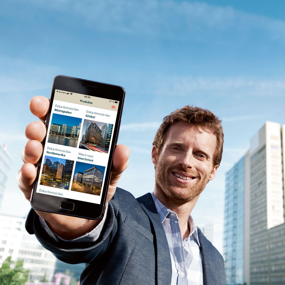 Mann zeigt Smartphone, darauf ist Gebäude und Deka Logo zu sehen