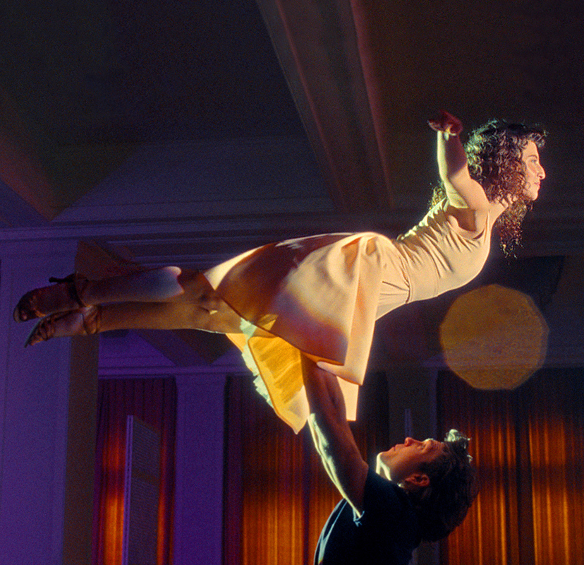 Halbtotale eines Tanzpaares während einer Hebefigur in einem großen Saal. 